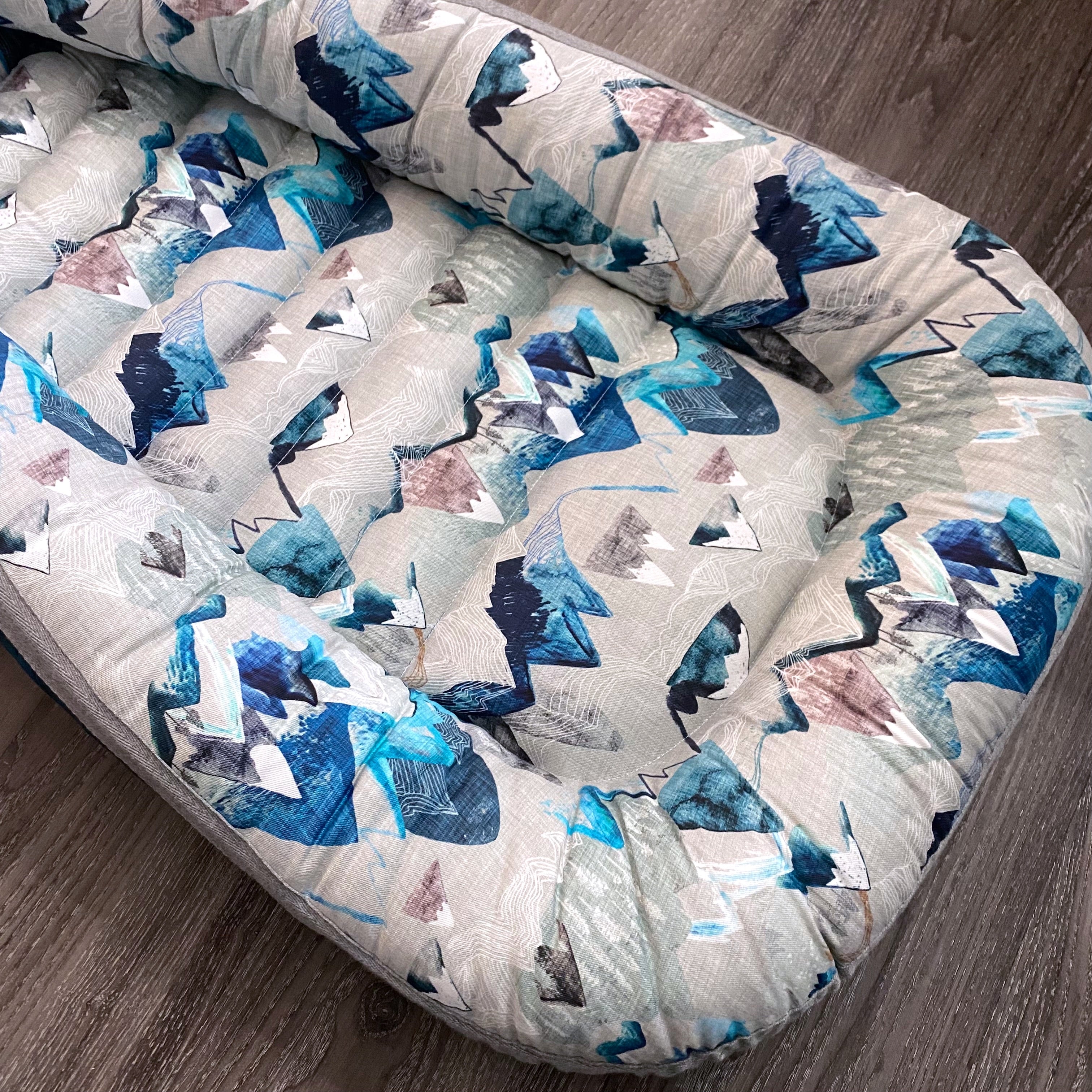 baby nest , baby lounging nest, co-sleeper, similar to dockatot and snuggle me products. This one is featured in a blue mountain design.