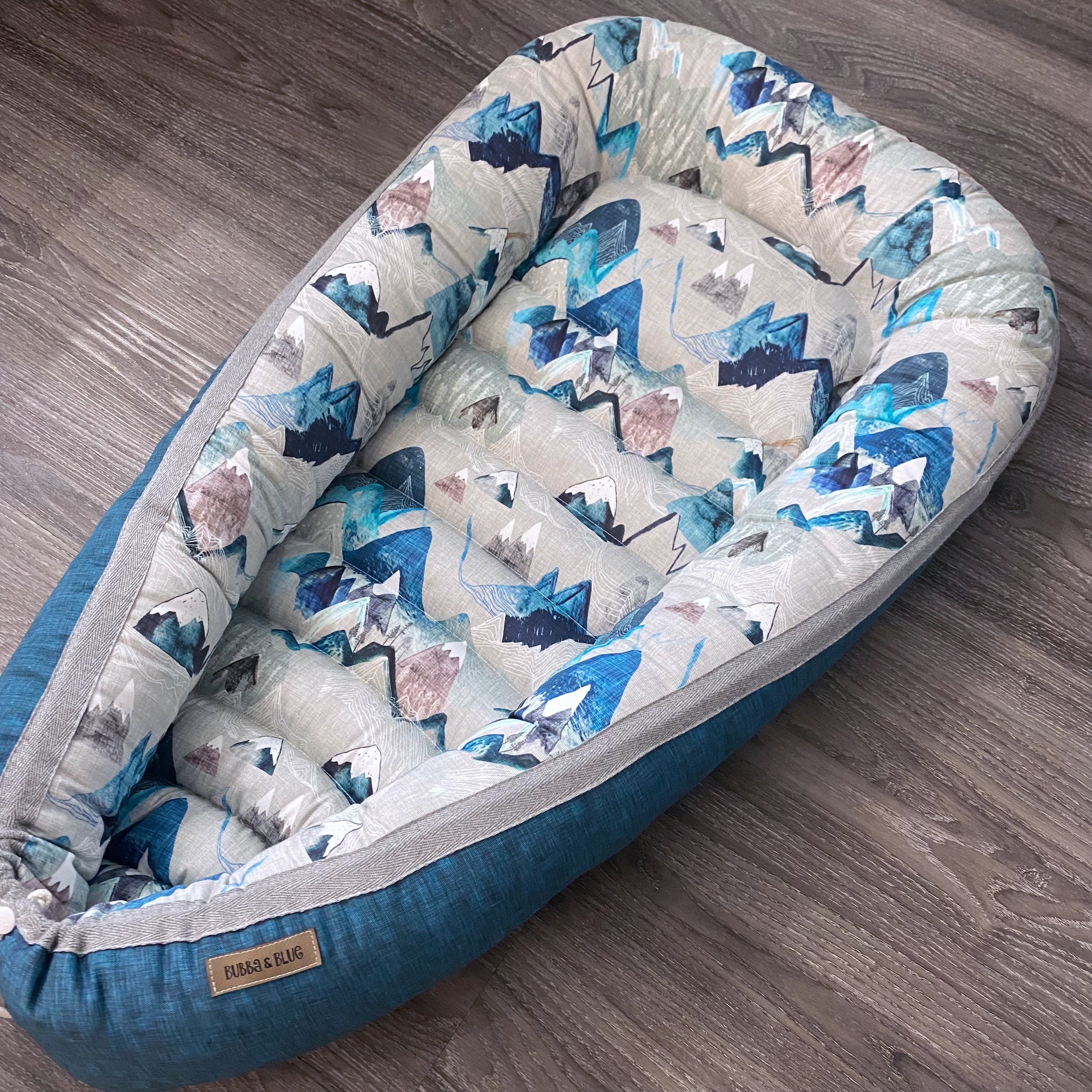 baby nest , baby lounging nest, co-sleeper, similar to dockatot and snuggle me products. This one is featured in a blue mountain design.